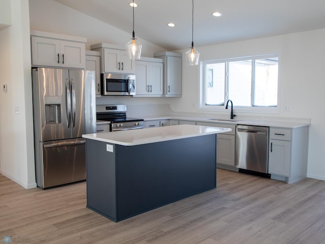 kitchen with appliances with stainless steel finishes, sink, vaulted ceiling, a center island, and decorative light fixtures