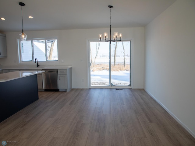 kitchen featuring stainless steel dishwasher, sink, hanging light fixtures, and dark hardwood / wood-style floors