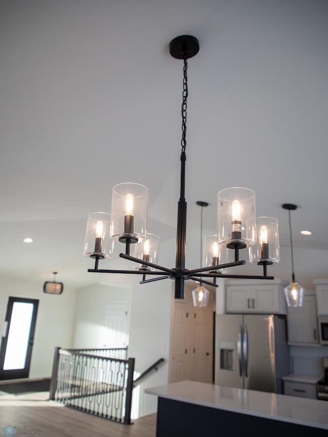 interior details with hanging light fixtures, range with electric cooktop, white cabinets, and stainless steel refrigerator with ice dispenser