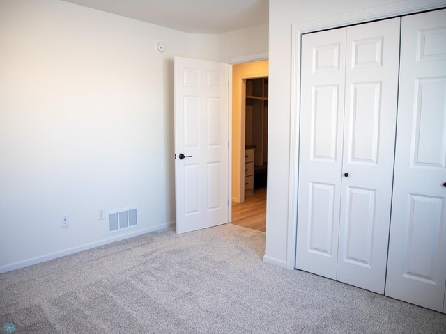 unfurnished bedroom with a closet and light colored carpet