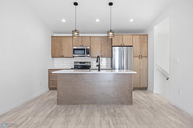 kitchen featuring stainless steel appliances, light countertops, and a kitchen island with sink