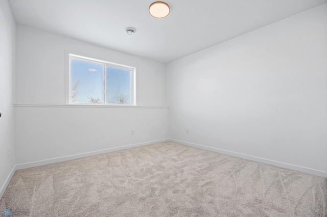 spare room featuring carpet and baseboards