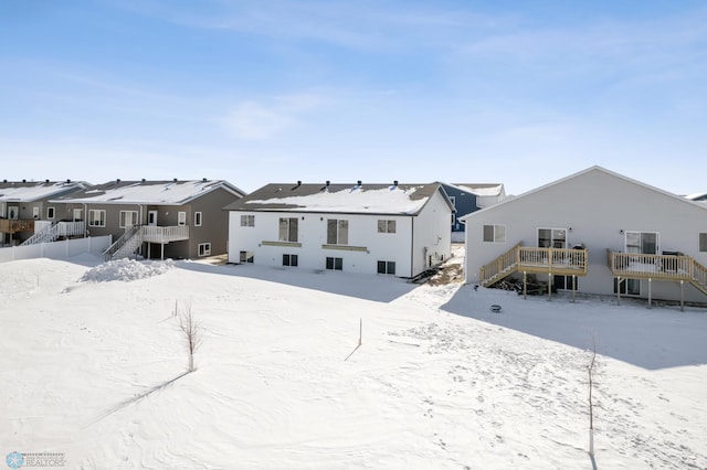 snow covered back of property with stairway and a residential view