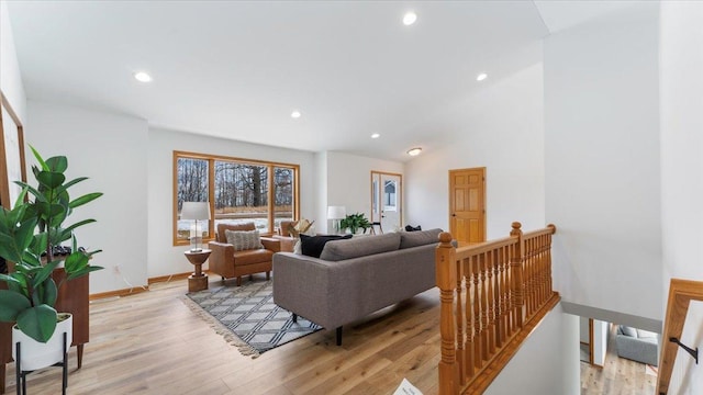 living room featuring light wood-type flooring, lofted ceiling, baseboards, and recessed lighting