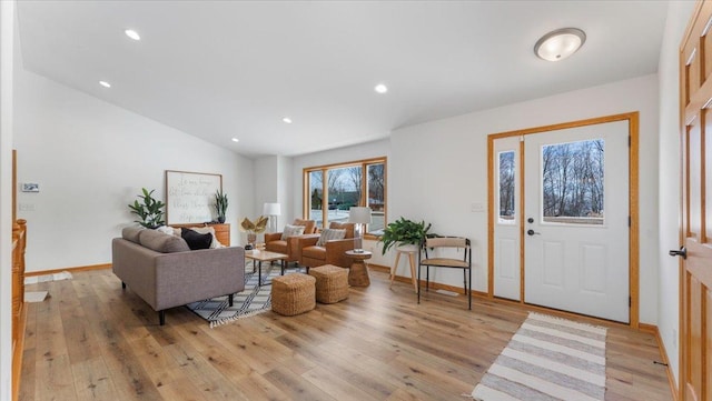 living area featuring vaulted ceiling, light wood-style flooring, and recessed lighting