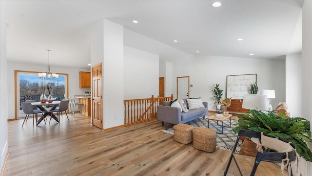 living area with high vaulted ceiling, recessed lighting, a notable chandelier, and light wood finished floors