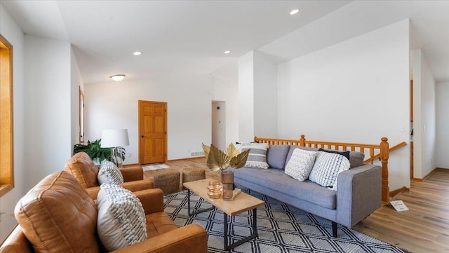 living room featuring visible vents, baseboards, lofted ceiling, wood finished floors, and recessed lighting