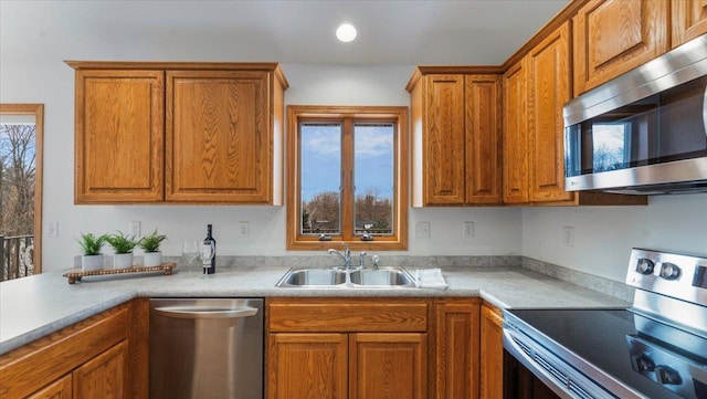 kitchen featuring plenty of natural light, appliances with stainless steel finishes, brown cabinetry, and a sink