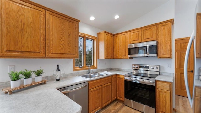 kitchen with stainless steel appliances, vaulted ceiling, light countertops, and a sink