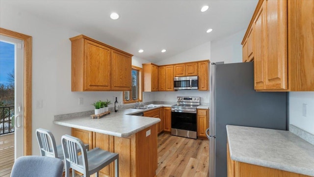 kitchen featuring stainless steel appliances, a peninsula, a sink, and light countertops