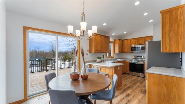 kitchen with visible vents, brown cabinetry, stainless steel appliances, light countertops, and a wealth of natural light