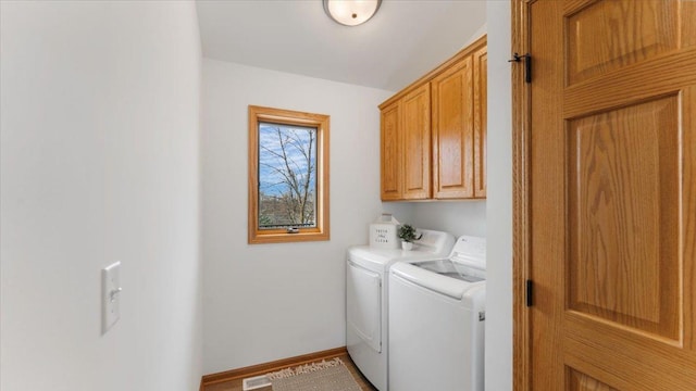 clothes washing area featuring cabinet space, baseboards, and washer and dryer