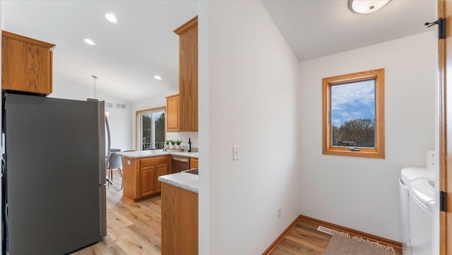 kitchen featuring lofted ceiling, light countertops, appliances with stainless steel finishes, independent washer and dryer, and light wood finished floors