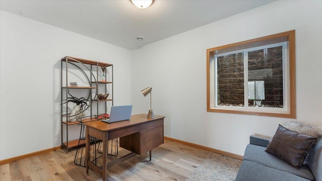 office space featuring light wood-style floors, baseboards, and a textured ceiling