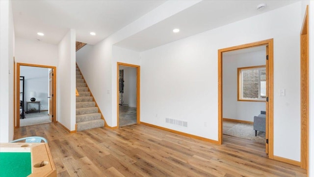 interior space with light wood-type flooring, stairway, baseboards, and visible vents