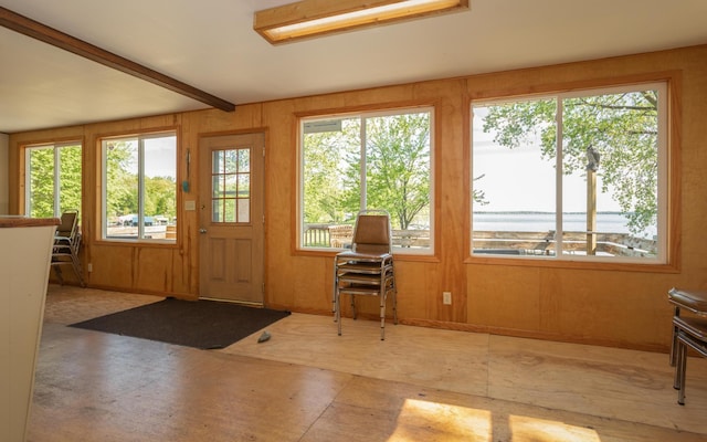 entryway featuring a wealth of natural light, beamed ceiling, and wood walls