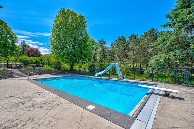 880 Norell Ave N, West Lakeland Twp, MN 55082 - view of pool featuring a diving board, a water slide, view of wooded area, and a patio area