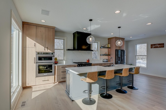 880 Norell Ave N, West Lakeland Twp, MN 55082 - kitchen featuring black fridge, modern cabinets, range hood, light countertops, and light wood-style floors