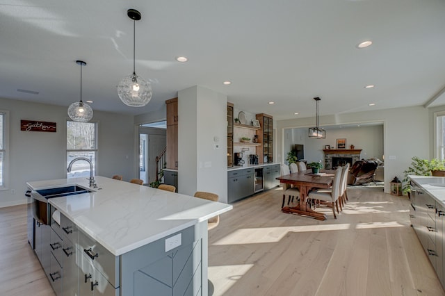 880 Norell Ave N, West Lakeland Twp, MN 55082 - kitchen with a sink, a fireplace, light wood finished floors, an island with sink, and recessed lighting