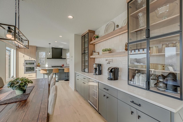 880 Norell Ave N, West Lakeland Twp, MN 55082 - kitchen featuring beverage cooler, gray cabinetry, tasteful backsplash, light wood finished floors, and stainless steel double oven