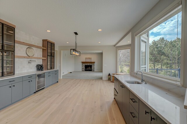 880 Norell Ave N, West Lakeland Twp, MN 55082 - kitchen featuring a sink, beverage cooler, gray cabinets, light wood-style flooring, and a fireplace