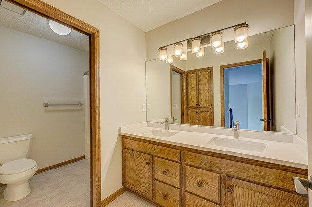 880 Norell Ave N, West Lakeland Twp, MN 55082 - full bath with double vanity, toilet, baseboards, and a textured ceiling