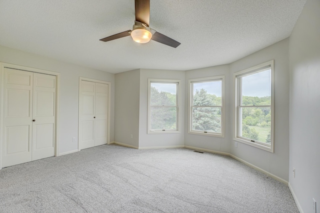 880 Norell Ave N, West Lakeland Twp, MN 55082 - unfurnished bedroom with carpet, multiple closets, baseboards, a textured ceiling, and a ceiling fan