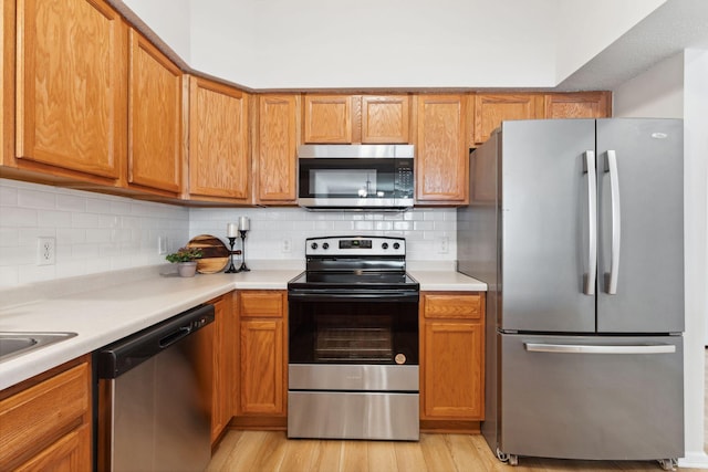 kitchen featuring tasteful backsplash, light wood-type flooring, and appliances with stainless steel finishes