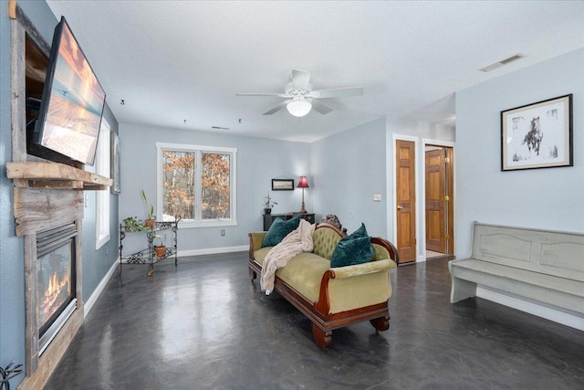 living room featuring ceiling fan, a large fireplace, and a textured ceiling