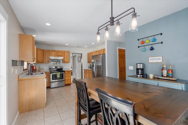 kitchen featuring appliances with stainless steel finishes, sink, light tile patterned floors, decorative light fixtures, and light brown cabinetry