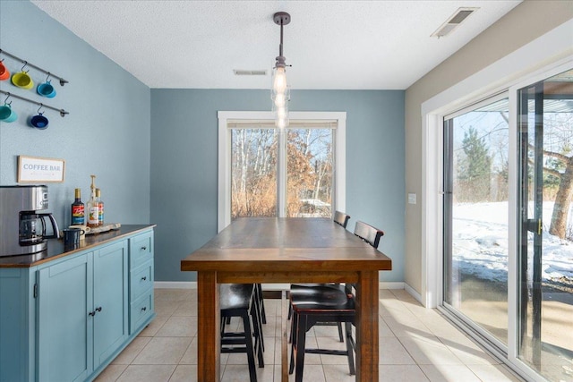 dining space featuring light tile patterned floors, a textured ceiling, and a wealth of natural light