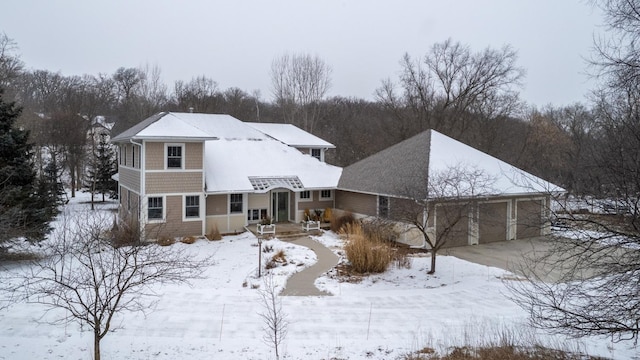 snow covered rear of property featuring a garage