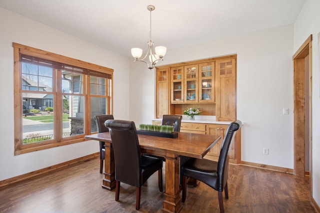 dining area featuring baseboards, a notable chandelier, and dark wood-type flooring