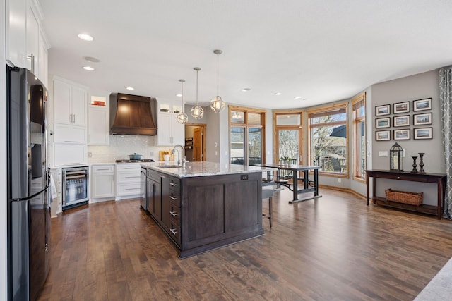 kitchen with beverage cooler, premium range hood, white cabinetry, a sink, and stainless steel appliances