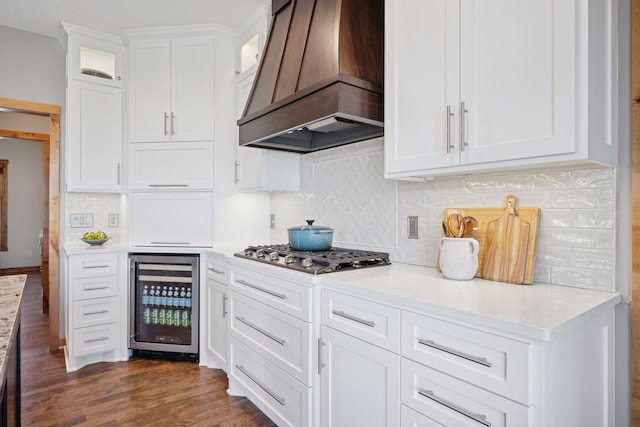 kitchen with glass insert cabinets, stainless steel gas cooktop, custom range hood, and beverage cooler