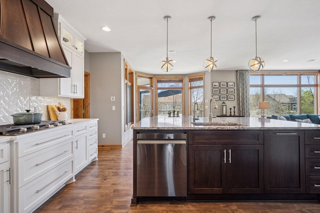 kitchen with backsplash, a sink, premium range hood, white cabinets, and stainless steel appliances
