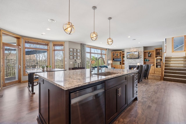 kitchen with dark wood-style flooring, a fireplace, dishwasher, a sink, and open floor plan
