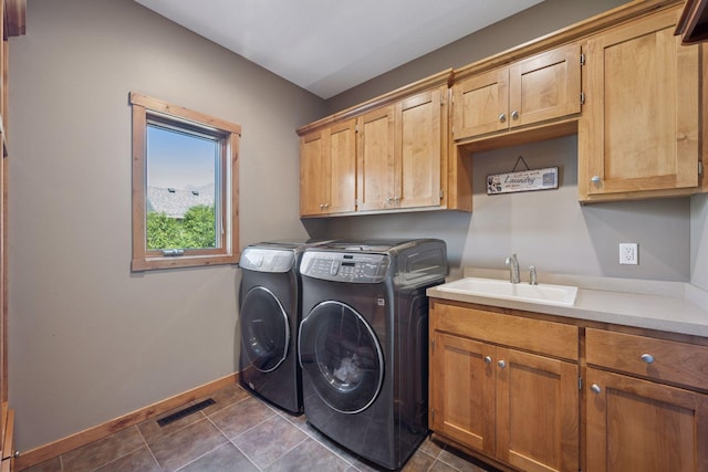laundry area with cabinet space, a sink, baseboards, dark tile patterned flooring, and washer and clothes dryer