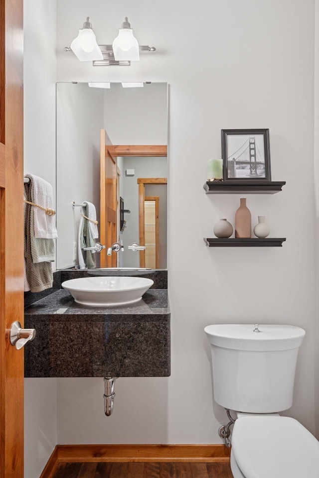 bathroom with a sink, wood finished floors, and toilet