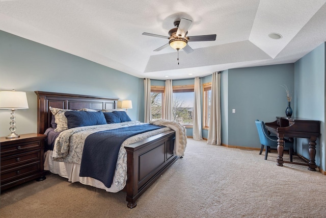 bedroom with a ceiling fan, a textured ceiling, a raised ceiling, baseboards, and carpet flooring