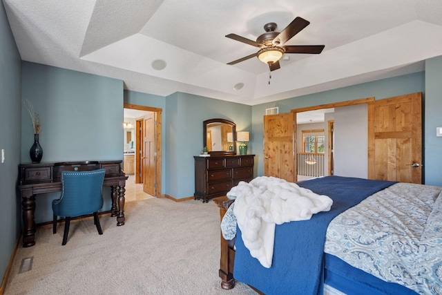 bedroom with ceiling fan, visible vents, baseboards, light carpet, and a tray ceiling