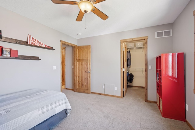 carpeted bedroom with a walk in closet, a ceiling fan, baseboards, visible vents, and a closet