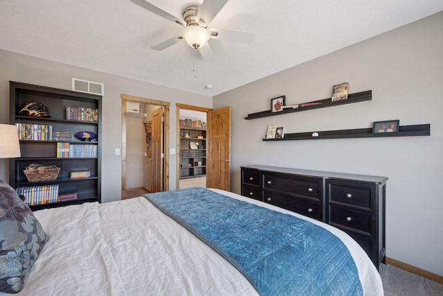 bedroom featuring visible vents, baseboards, ceiling fan, a spacious closet, and carpet