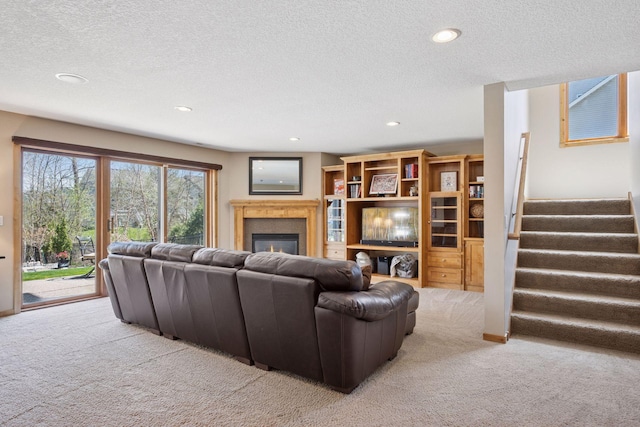 living room with stairs, a glass covered fireplace, recessed lighting, a textured ceiling, and carpet flooring