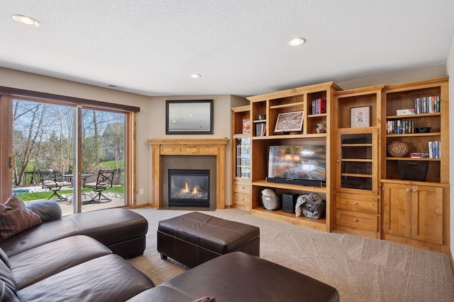 living room featuring carpet floors, recessed lighting, a textured ceiling, and a glass covered fireplace