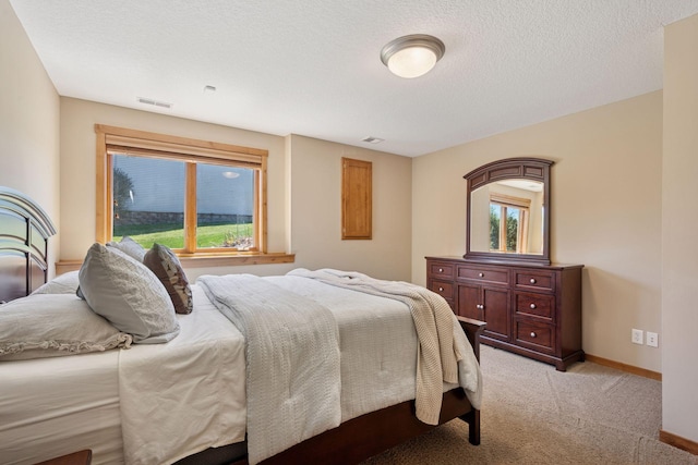 bedroom featuring baseboards, light carpet, a textured ceiling, and visible vents