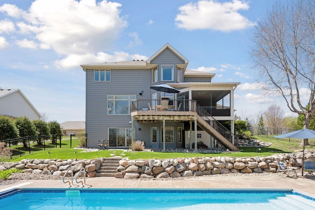 back of property featuring a sunroom, a yard, stairway, and a fenced in pool
