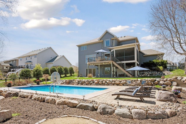 view of pool featuring stairway, fence, a patio area, and a sunroom