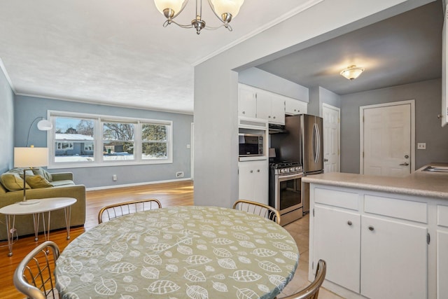 kitchen with gas range, white cabinetry, hanging light fixtures, and light hardwood / wood-style flooring