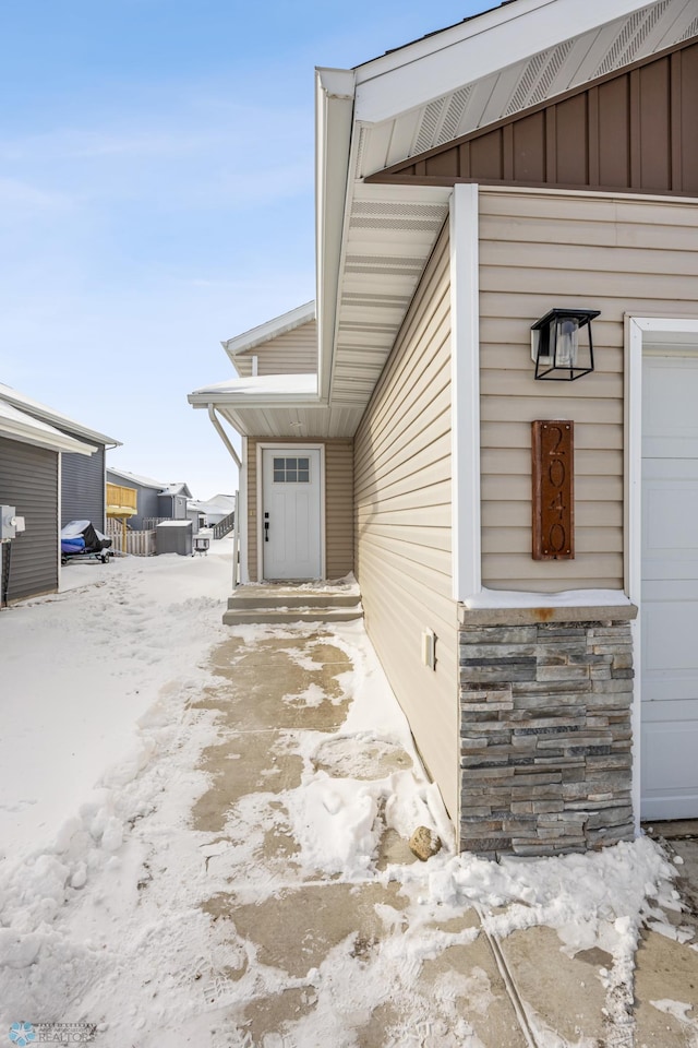 snow covered property entrance featuring a garage